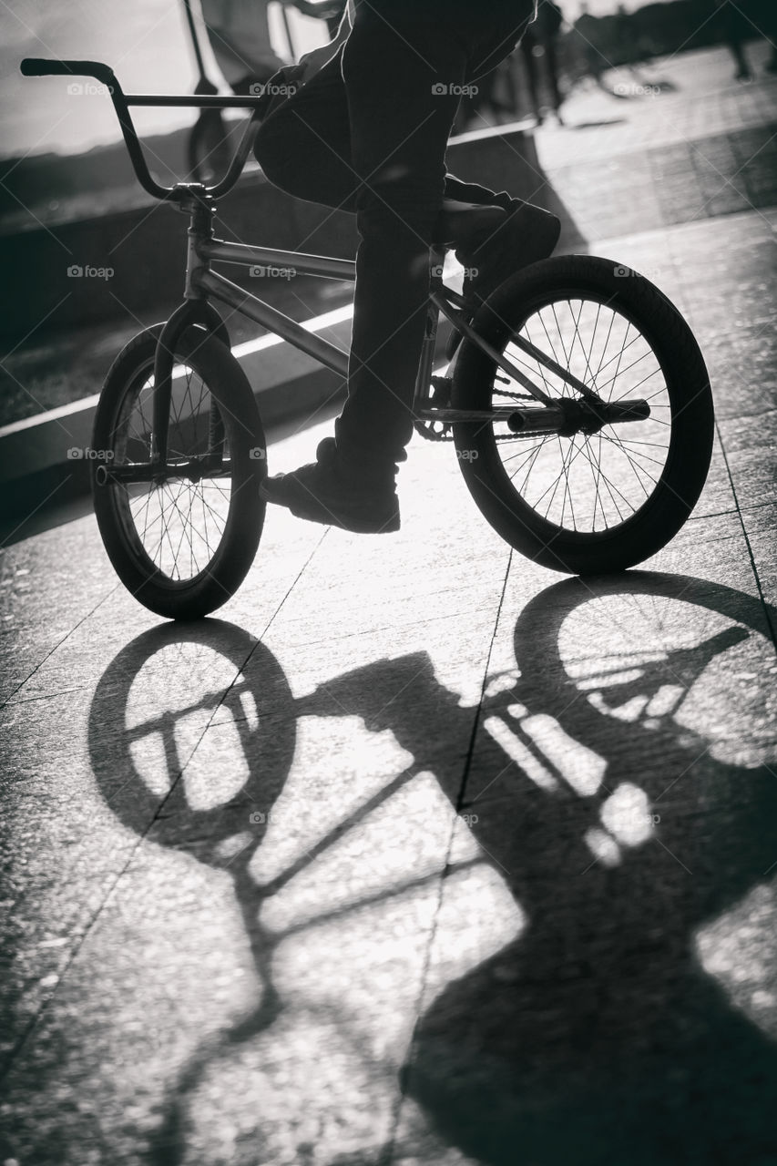 Teenager riding a bicycle, silhouetted r
shadow on the road