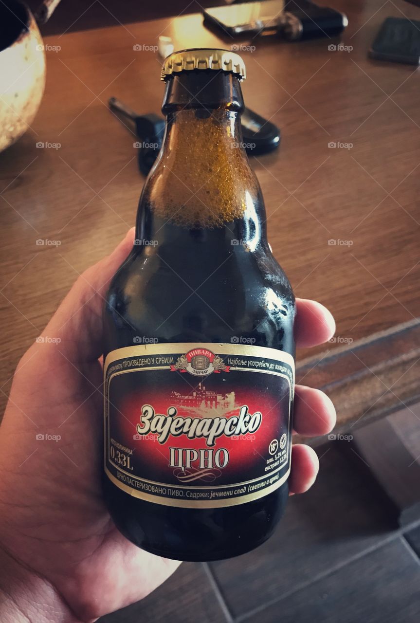 Men holding small bottle of dark beer 