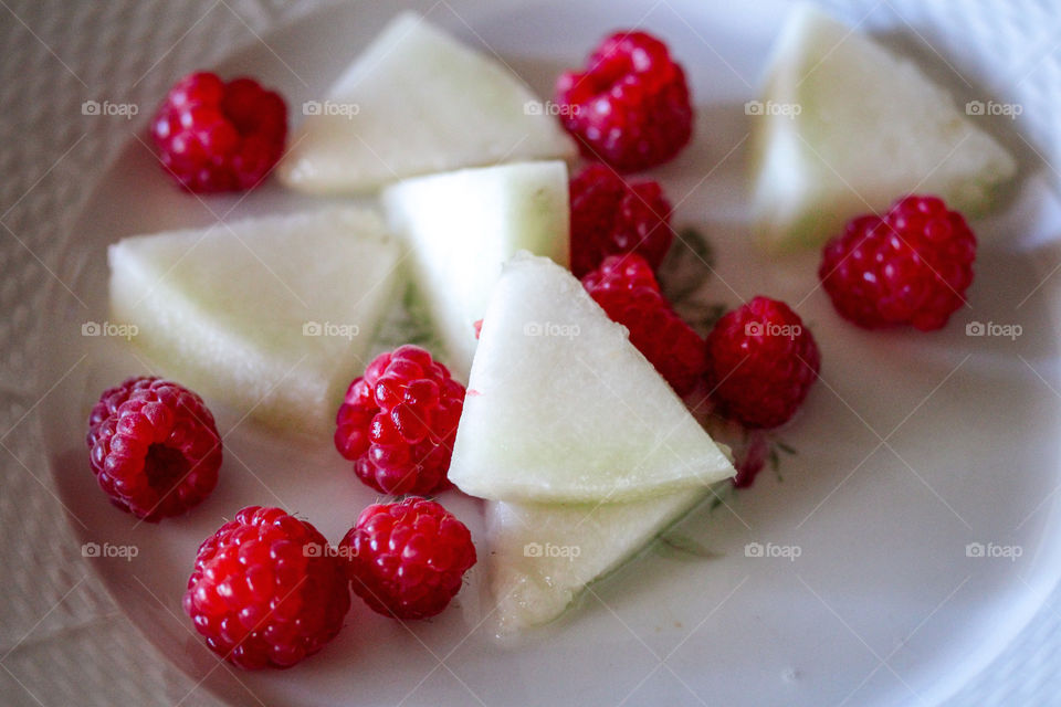 Red berries and slices of a melon at the plates