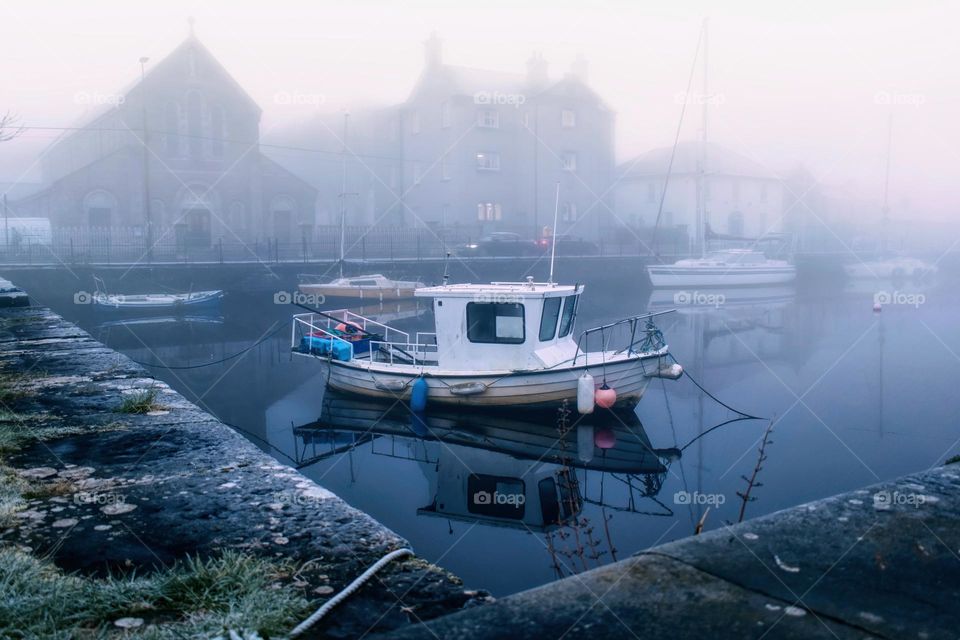 Old wooden boat on cold foggy morning at Claddagh, Galway City, Ireland