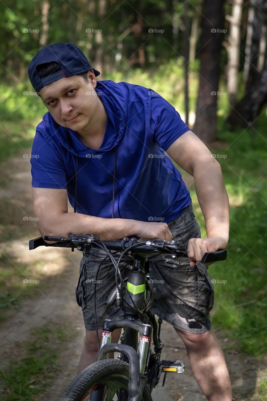 A young man in a cap ride a bicycle in the summer in the park. Fintes healthy lifestyle