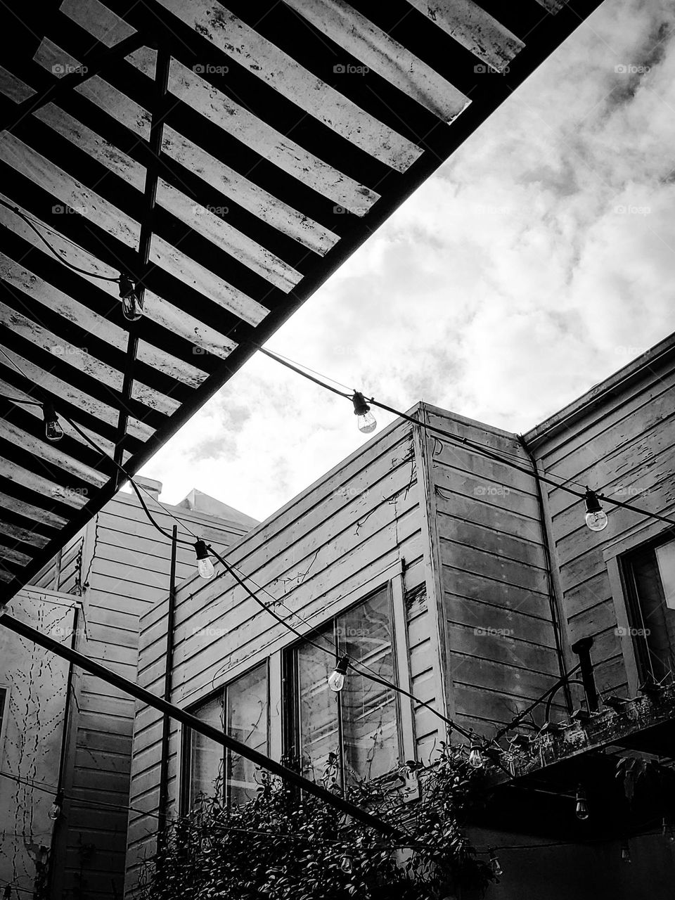 Black and white view looking up from a backyard patio in San Francisco California with different geometric shapes , clouds 