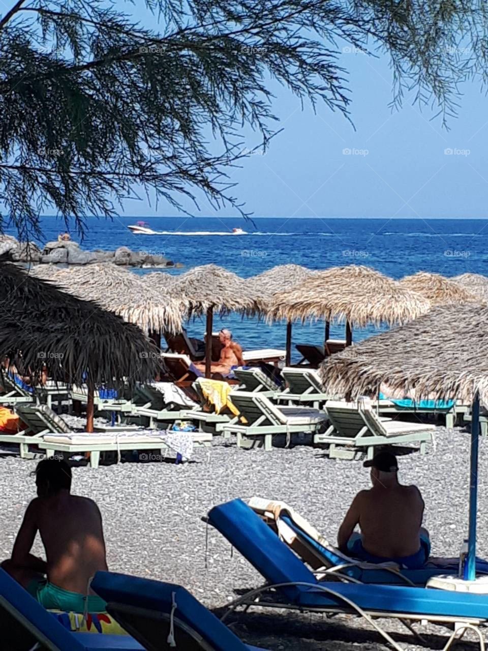 Morning at the sea. Umbrellas and sunbeds waiting for tourists to to be used for relaxing, carefree moments. Beautiful blue sea ready to for watersport lovers...