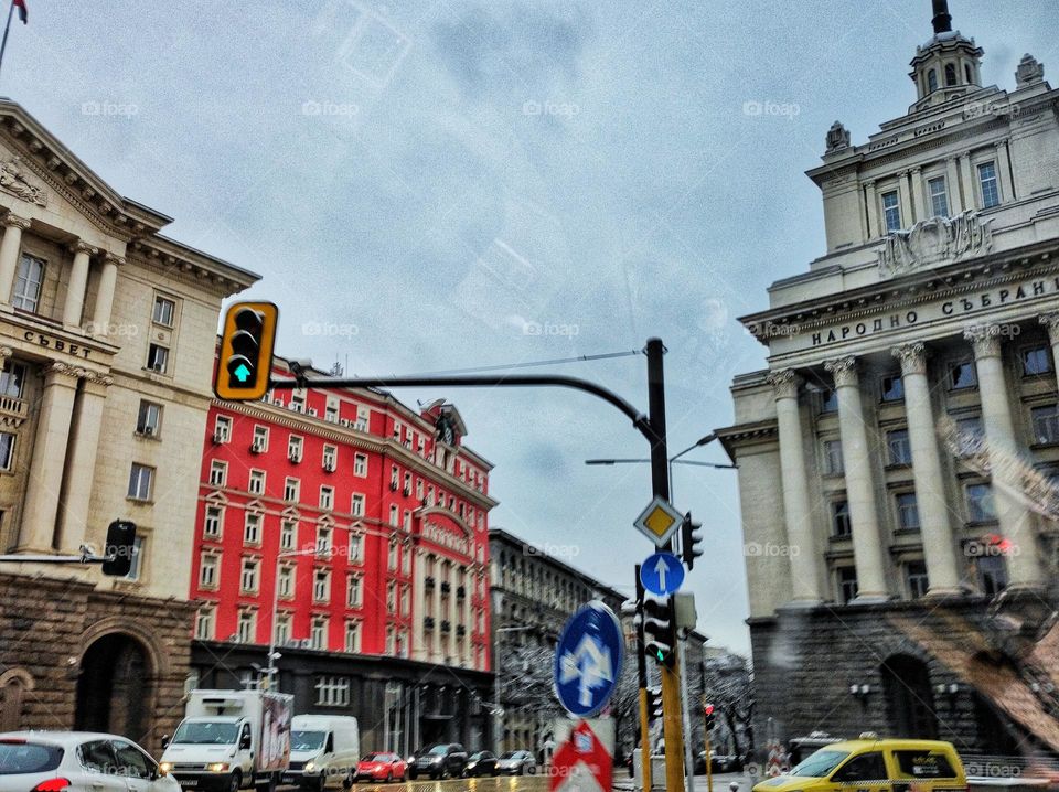 A busy street right in the centre of the capital city of Bulgaria, with moving cars and beautiful buildings in the cold winter