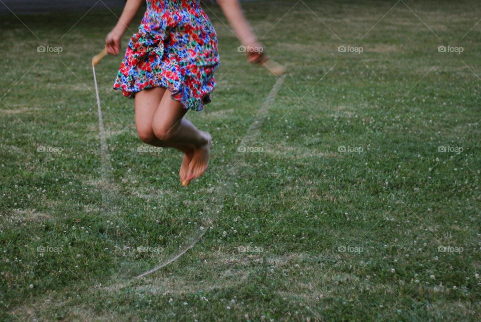 Woman with colorful dress jumping on rope at the park