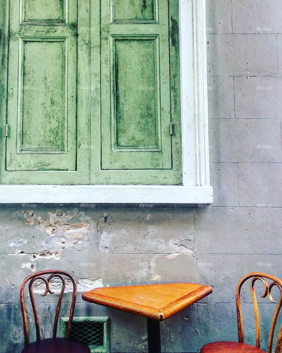 Chairs and table under a large wooden window