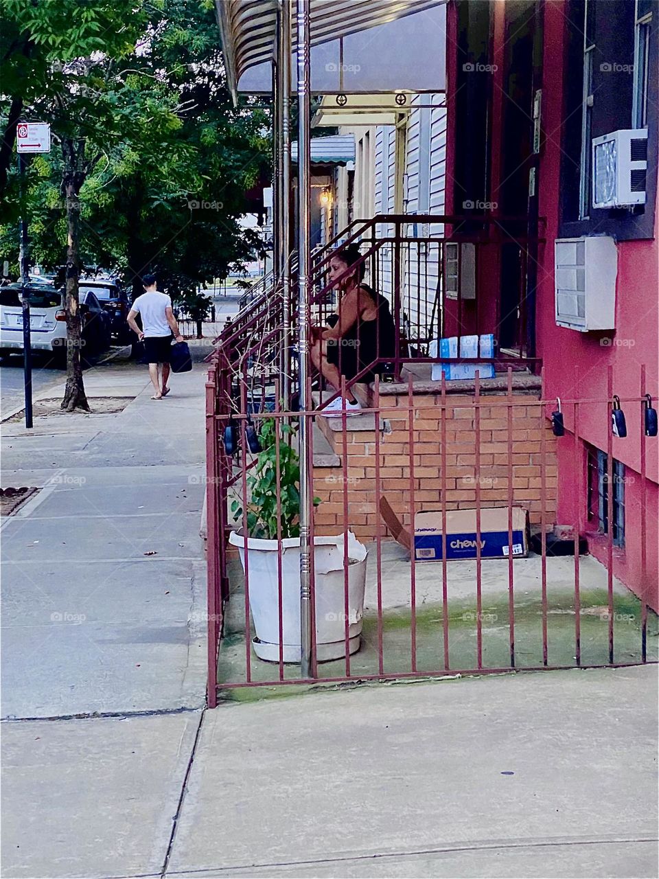 This is “Clay Street” in “Greenpoint”, Bklyn opposite the “BOX HOUSE HOTEL” at twilight time before nightfall on an Indian summer evening in September 2023. A lady is enjoying the scenery sitting on the stoop to her building. Hypnotic Productions