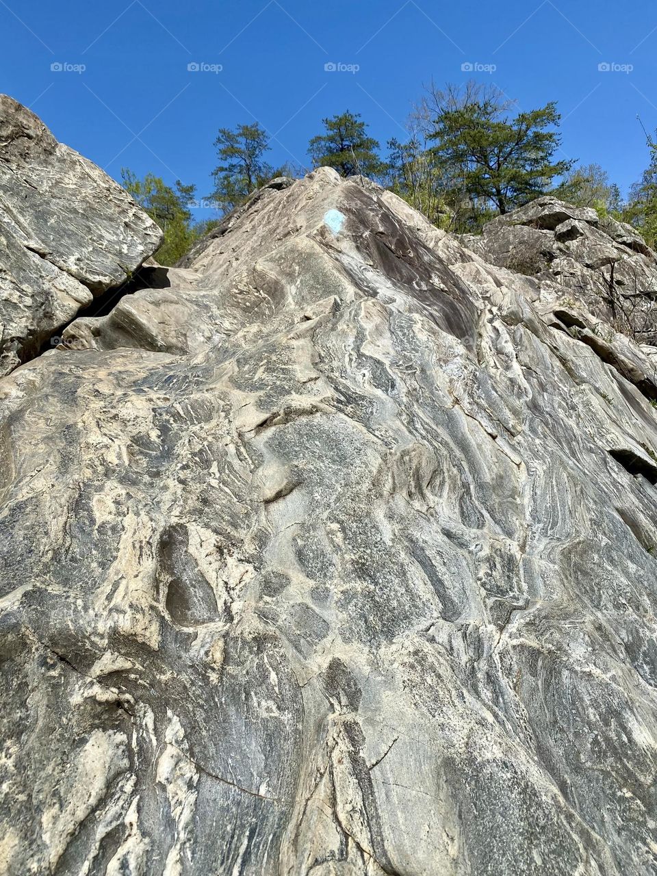 A blue blazed hiking trail going up a rock face