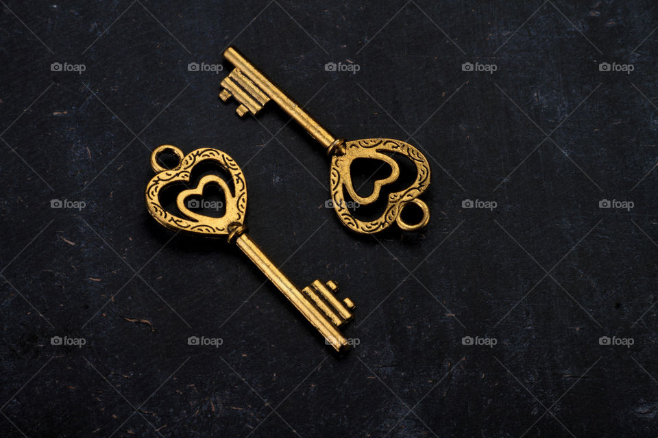 Heart shaped golden antique keys on black textured background