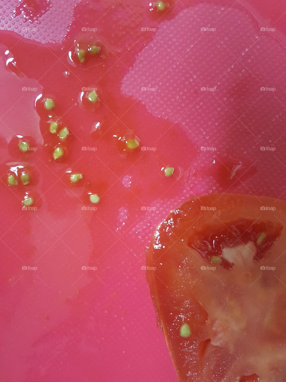 Tomato slice and seeds on red background