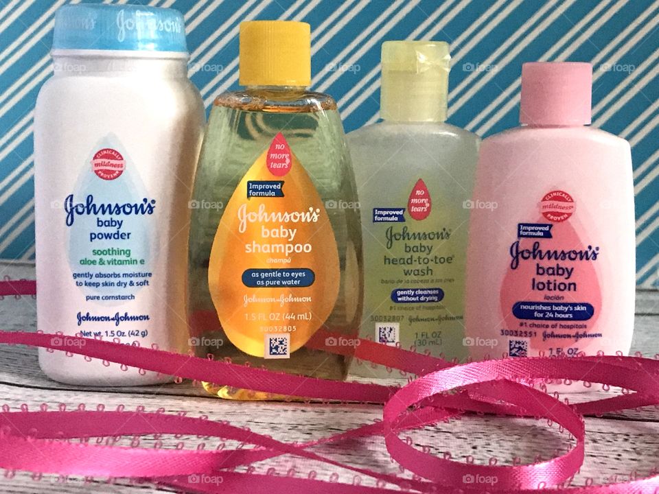 Johnson and Johnson baby lotion, shampoo, head to toe wash and powder on a blue and white background with a pink ribbon 