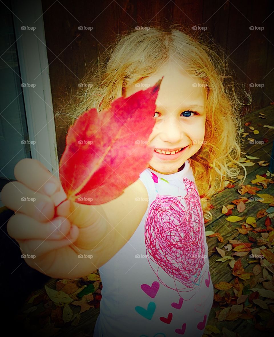 Little Red Leaf. Sweet little girl holding up a bright red leaf. 