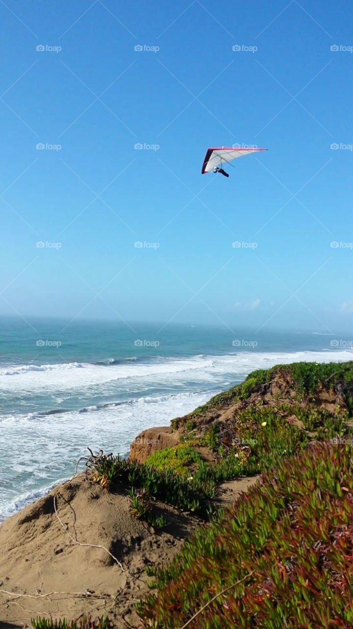 hang gliding by ocean