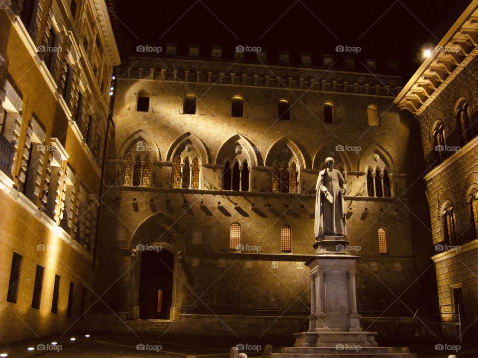Italian statue backlit at night in stone courtyard 