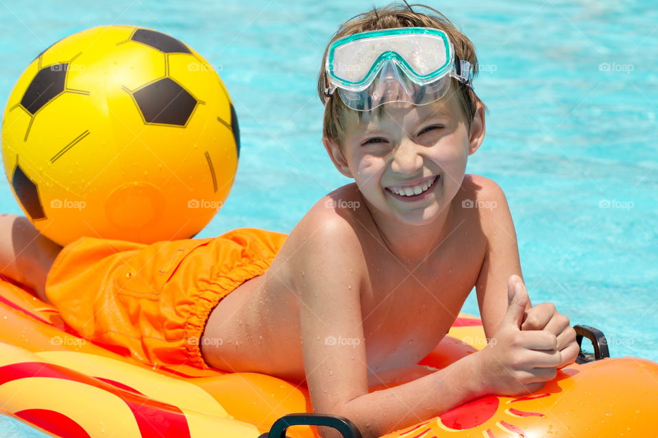 Smiling boy lying on inflatable on swimming pool
