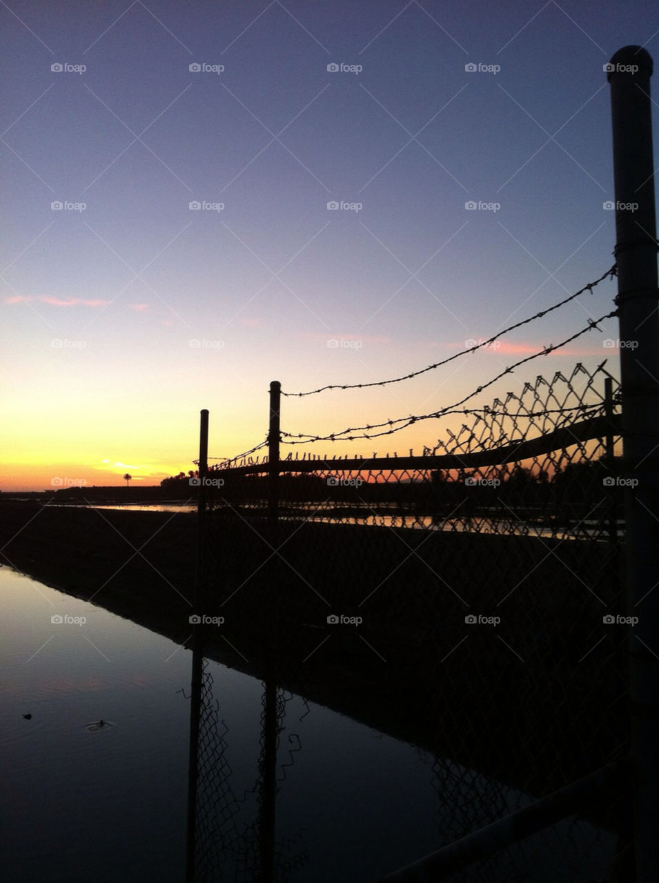 Barbwire fence over sunrise sunset