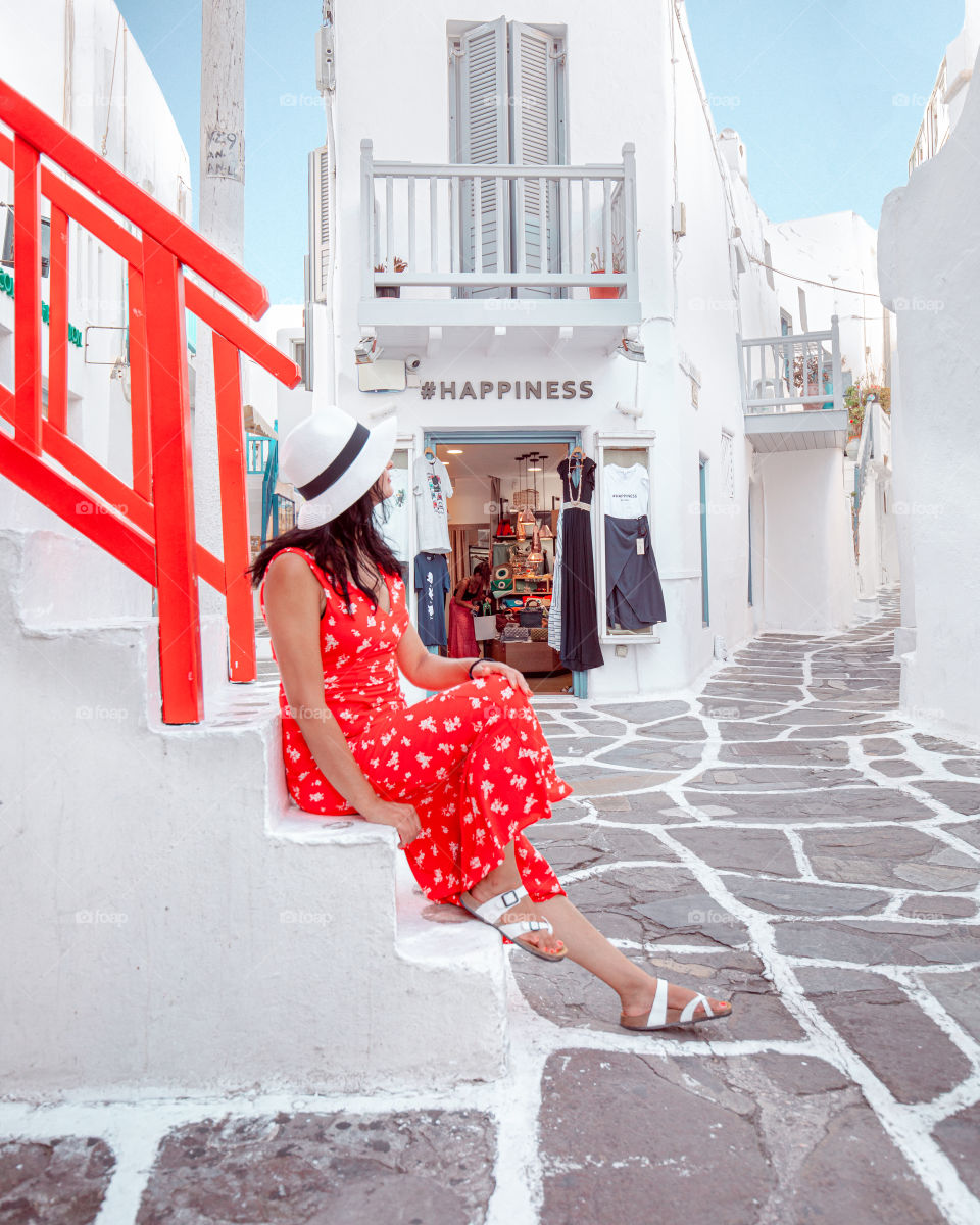 Woman in red dress in the streets of Mykonos greek island. 