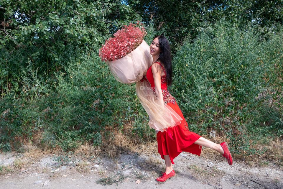 Woman Dances with a Large Bouquet of Red Flowers