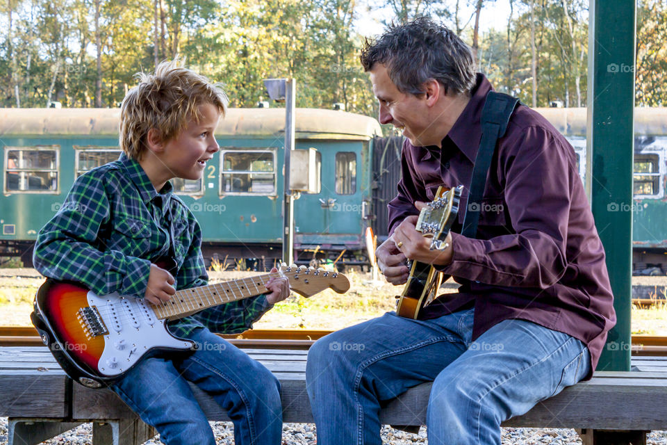boy with his dad playing guitar together
