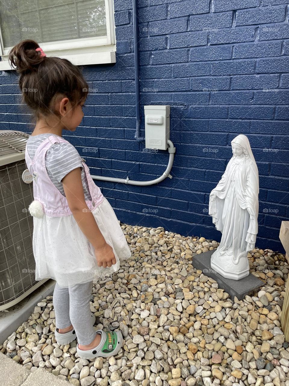 Little girl talks to Mary Statue, asking Mary questions, Mary Statue as decoration in backyard, little girl understanding religion 