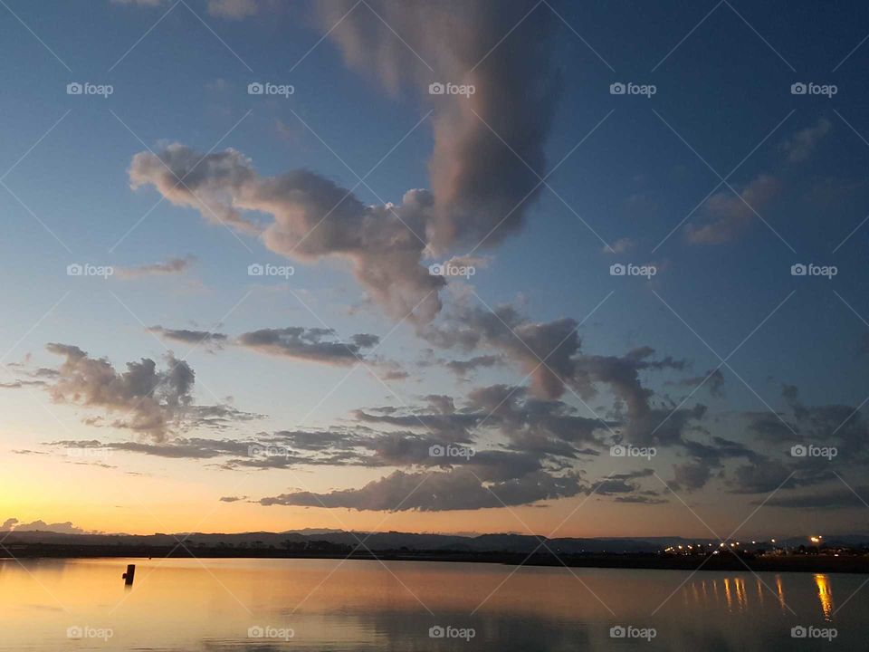 A beautiful sun set over pandora pond in Napier. The gorgeous golden glow with amazing cloud formations. A single drum sits alone to the left in the water and the reflections are of the clouds on the water.