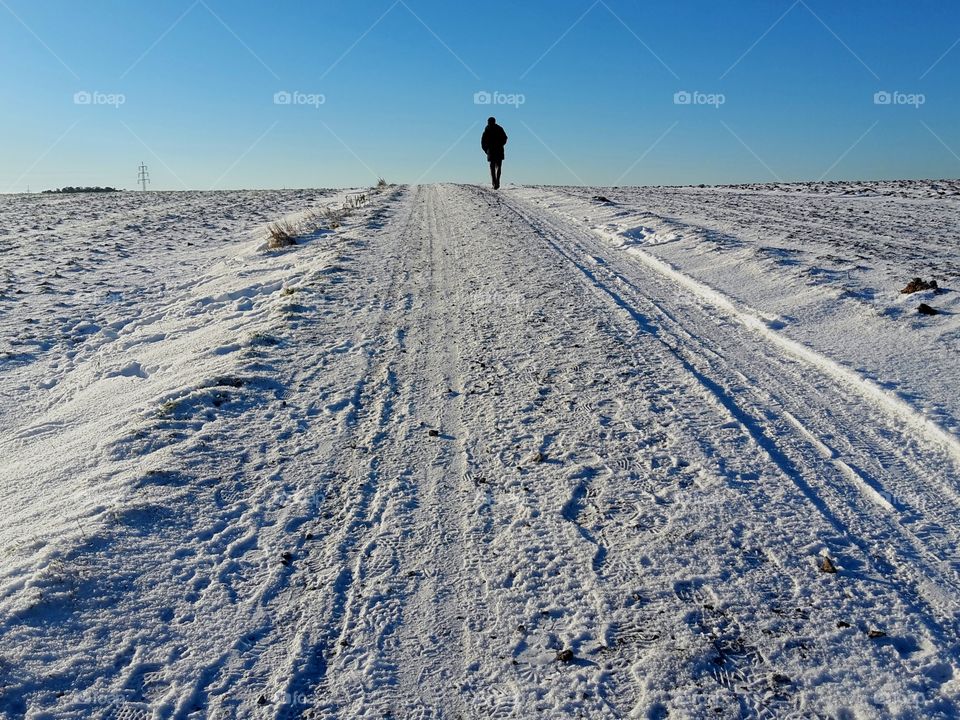 Man walking in a snow landscape between field up