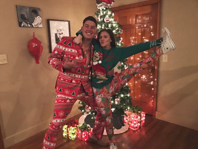 Couple posing in front of decorative Christmas tree