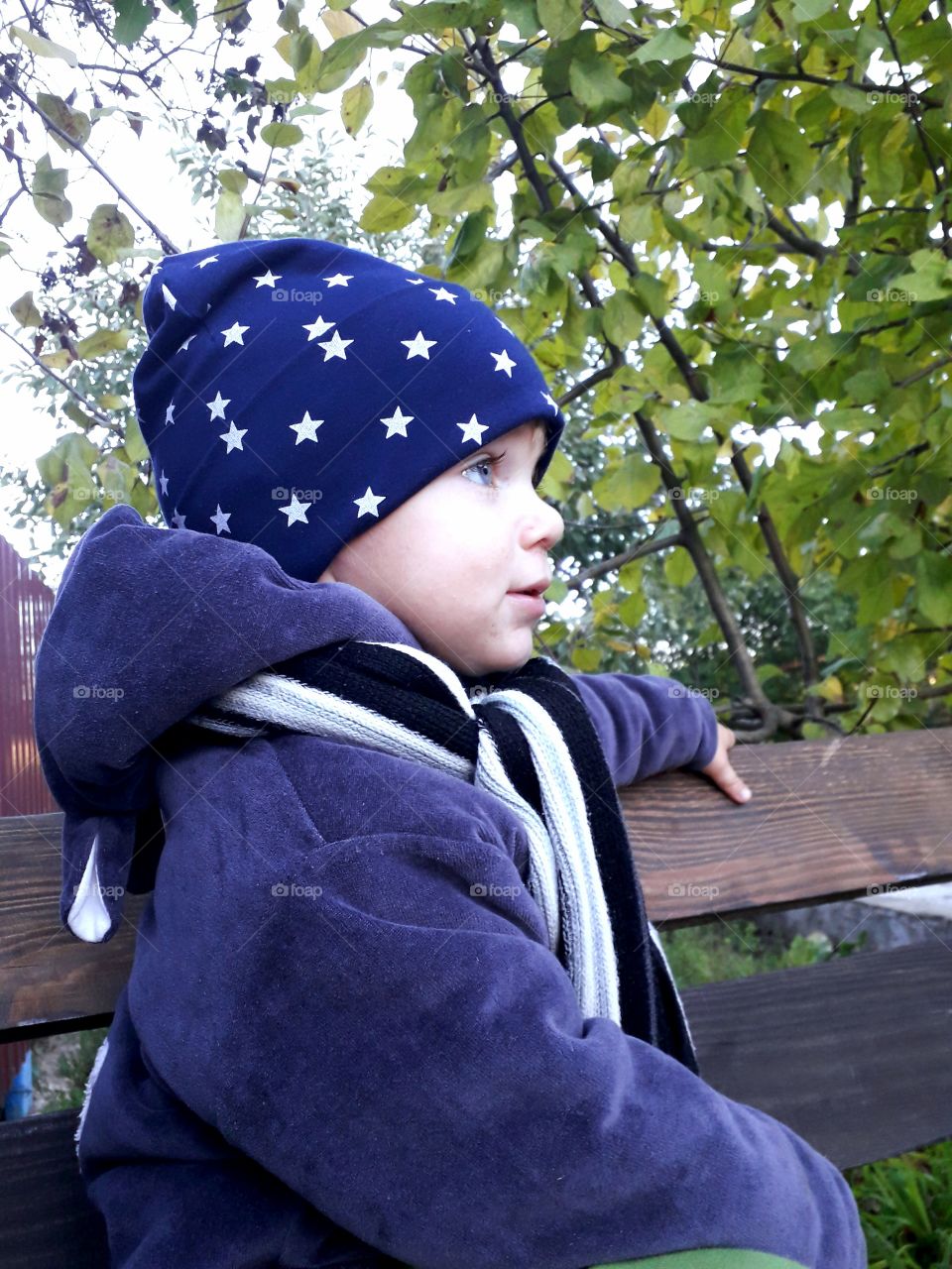 a little boy is sitting on the bench