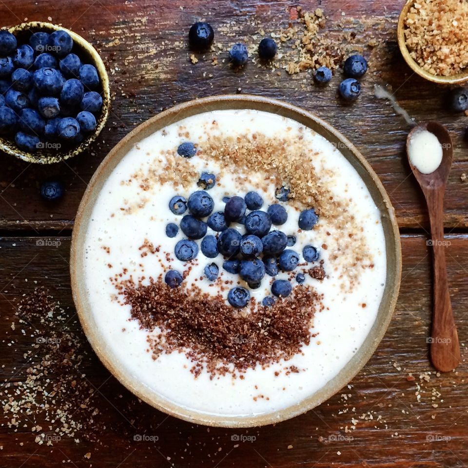 Banana Almond Smoothie Bowl with fresh blueberries and sweet crumb topping in a ceramic bowl on a rustic wood table.