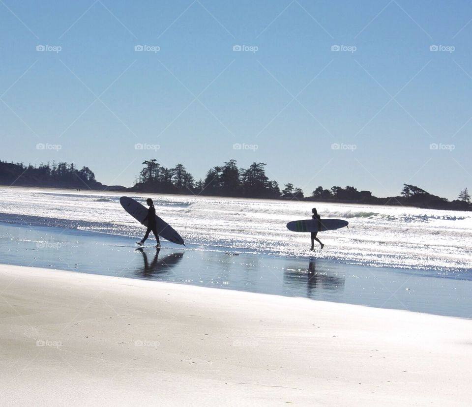 Surfers on Pacific Ocean under blue skies and in glistening water