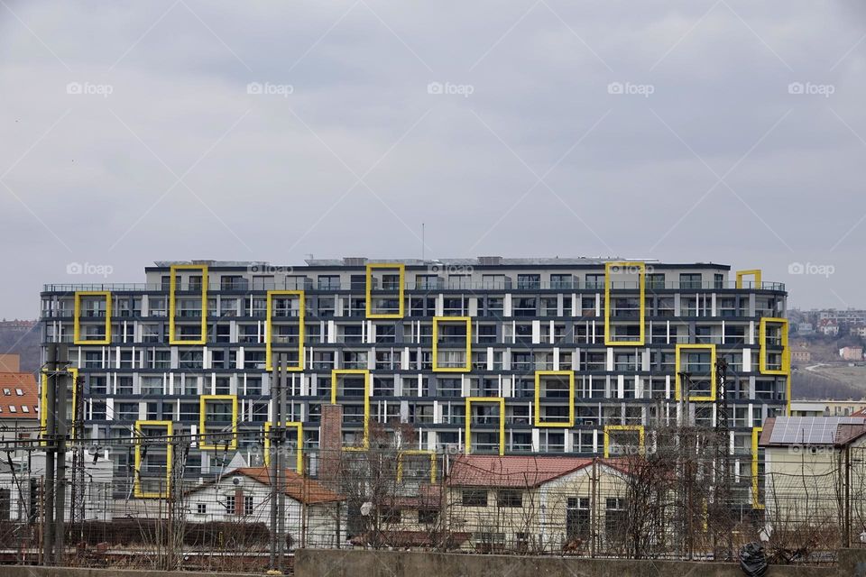 Modern residential building in Prague with a facade decorated with yellow squares and rectangles. In the foreground the station and the tracks.