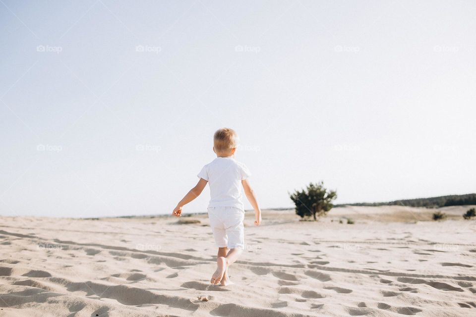 Boy in white clothes run on desert