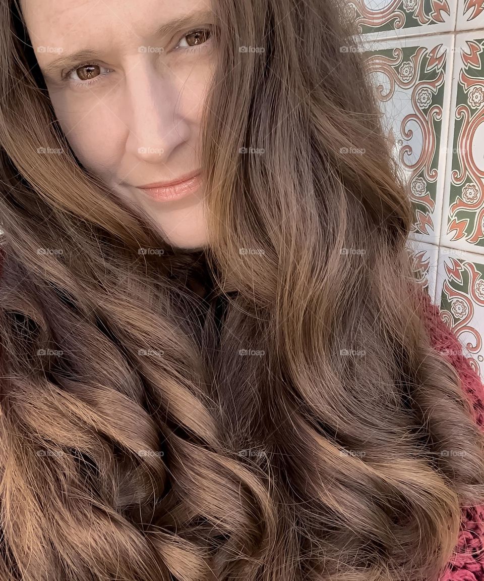 Middle-aged woman with long, curly hair in shades of brown