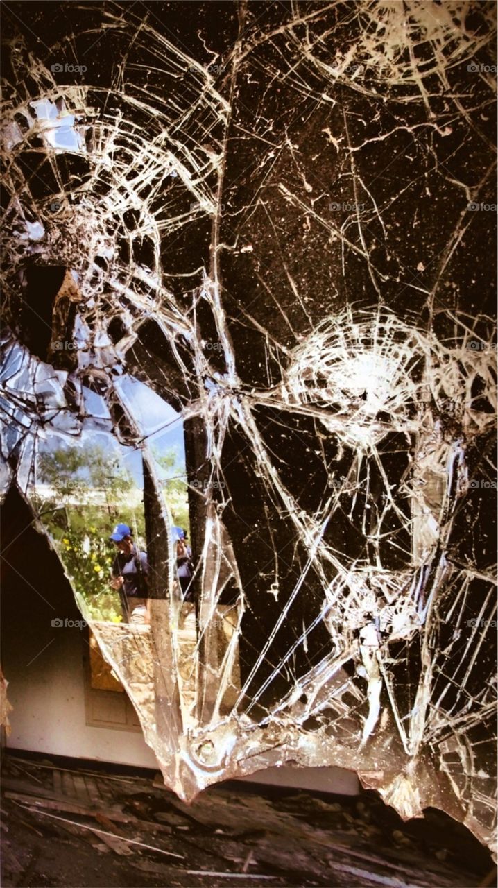 Reflection Of A Person In Shattered Glass On A Window At An Abandoned Hotel