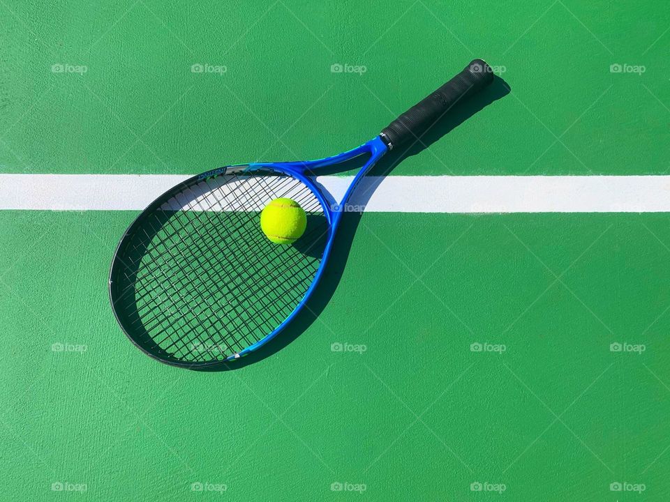 Tennis racket and ball on green background