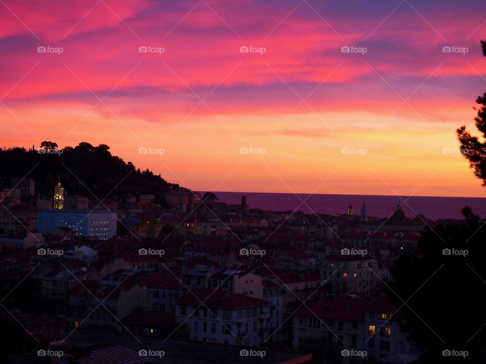 View of colorful sky at sunset overlooking the old town and sea in Nice, France.