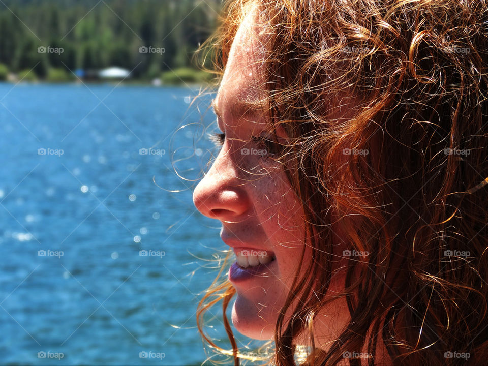 Pretty young redhead American girl near a lake