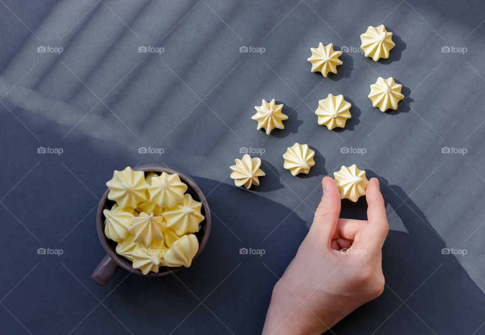 Flat lay made by yellow meringue on gray background.