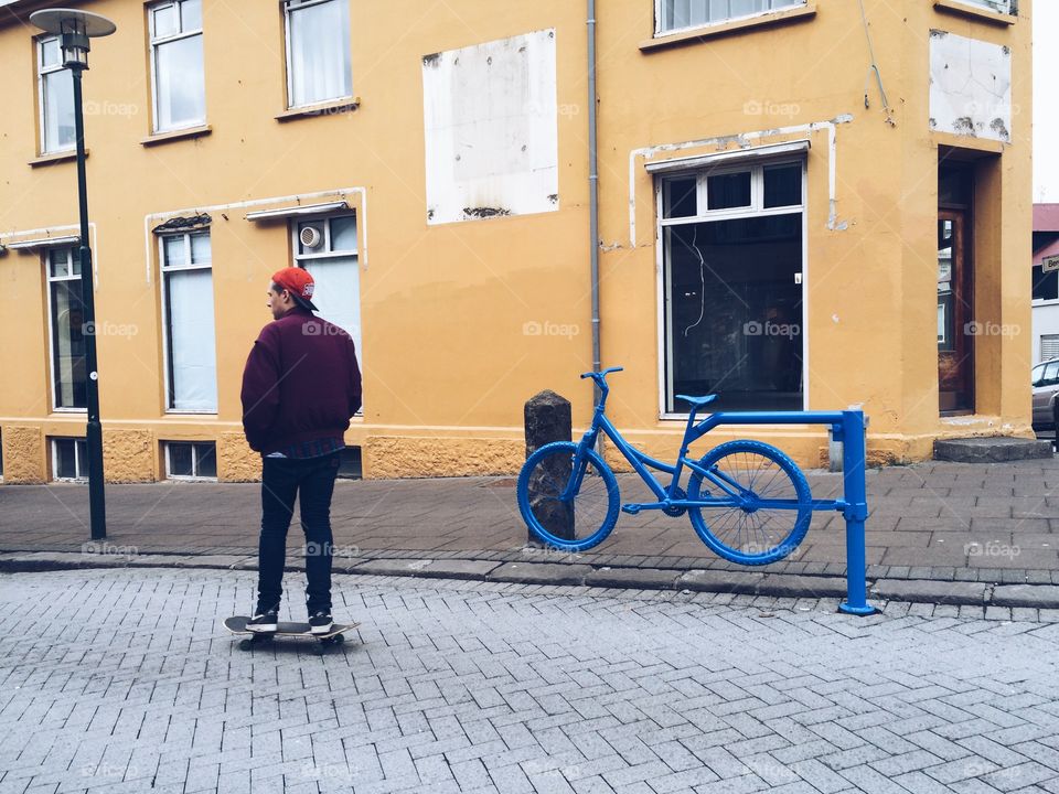 Skateboarder rolling past a blue bicycle gate in Iceland. Creative bike gate with skater cruising past. 