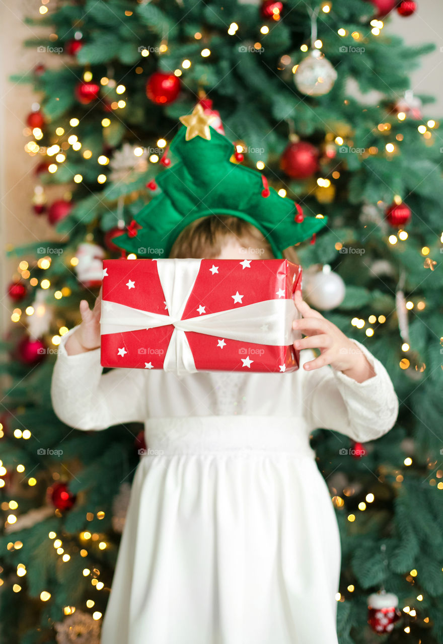 Child with gift in front of Christmas tree