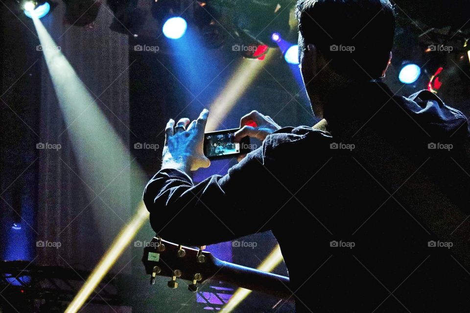 Marc from the band OAR (Of a Revolution) takes a photo of his band using his iPhone at a concert