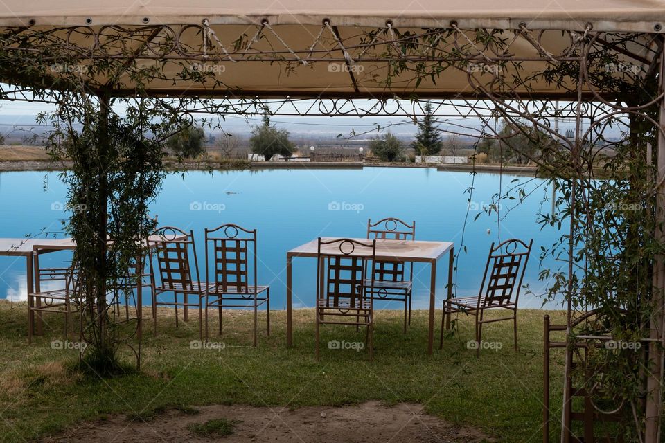 Cafe with metal furniture on the shore of a small blue lake