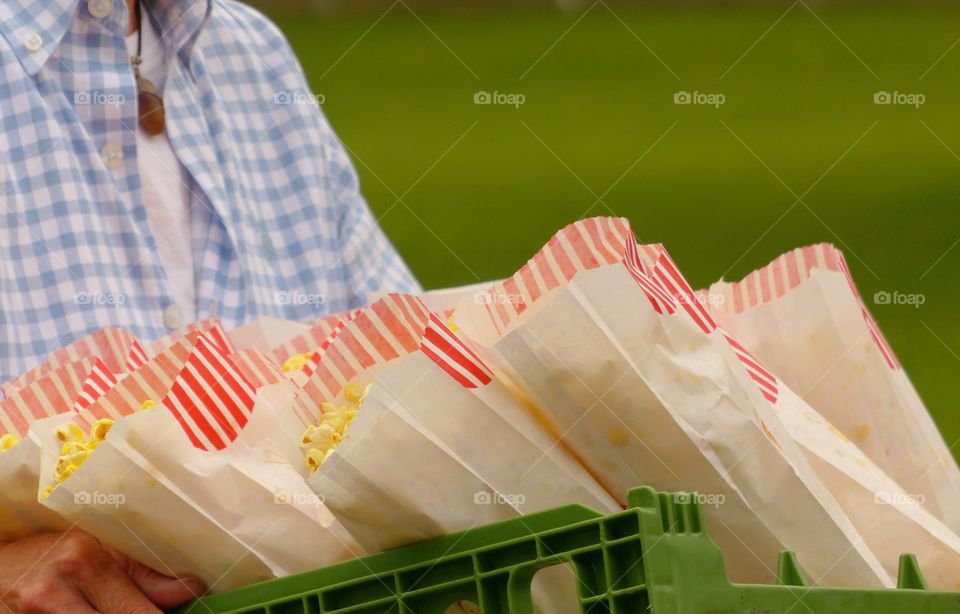 Person holding a tray full of pop corn bags