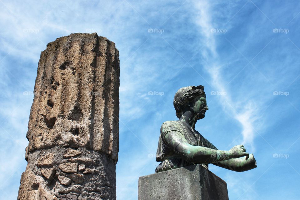 ancient destroyed column and antique statue of Apollo against the blue sky. Italy, Pompeii