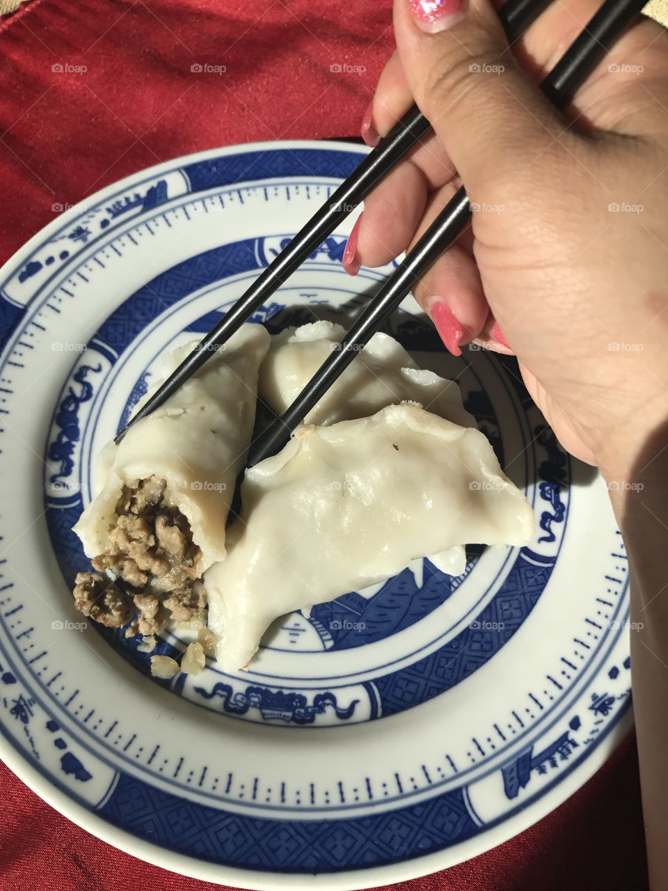 Hand holding chopsticks of dumplings