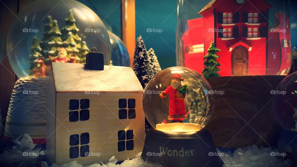 Holiday snowglobes and ornaments set a scene to welcome the Christmas season. Santas, houses, and trees give a landscape feeling.