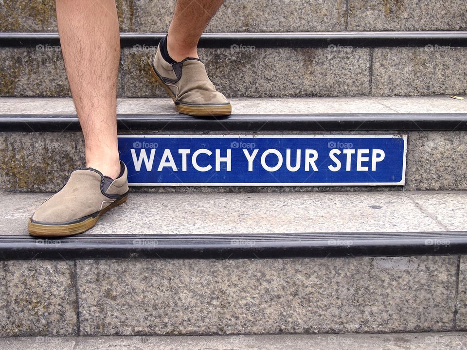 watch your step sign and a pair of feet