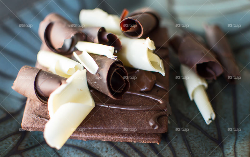 Dark chocolate biscuit covered with chocolate sauce and white chocolate and dark chocolate shavings and curls gourmet food photography background 