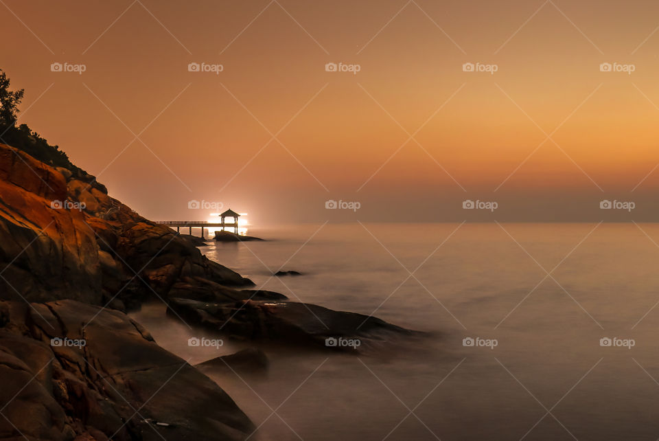 A Passing Fishing Vessel behind an Ocean View Deck during Dawn moments. 