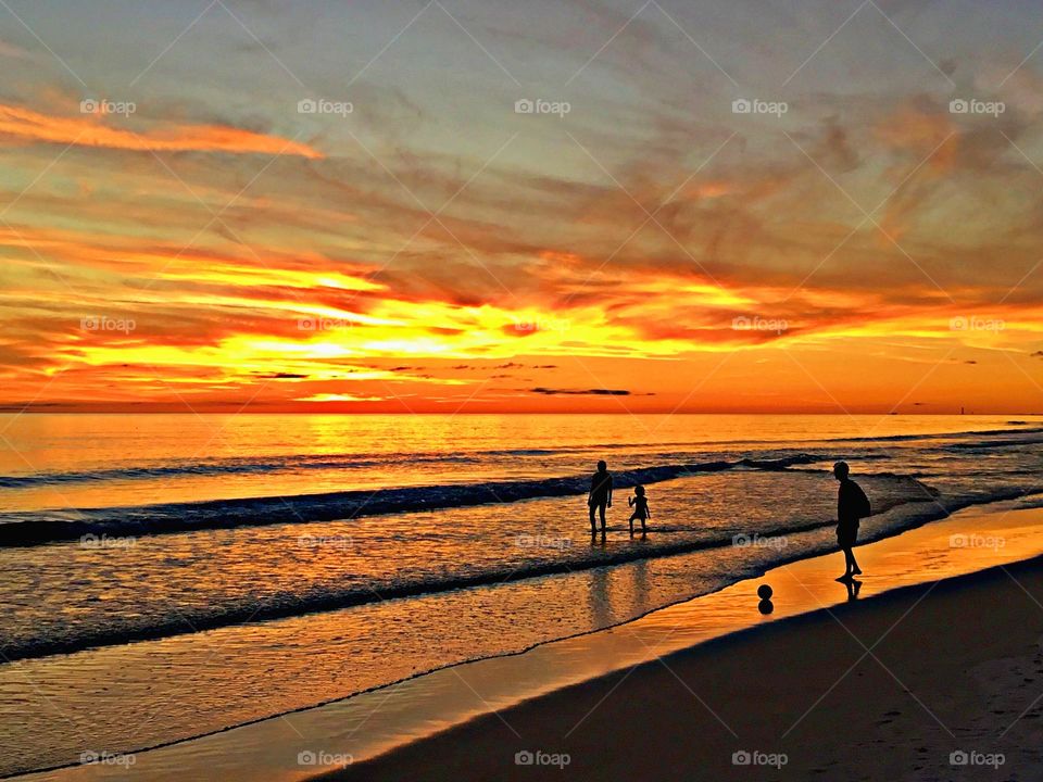 Battle: Summer vs Spring - Beach sunset - A father, mother and daughter playing on the sandy beach of the Gulf of Mexico during a magnificent and colorful sunset. Concept summer vs spring.